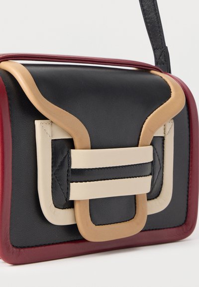 Μικρή ορθογώνια δερμάτινη τσάντα χειρός με μπλοκ χρωμάτων σε μαύρο, μπεζ και μπορντό, και μια φαρδιά μπεζ αγκράφα στη μπροστινή πλευρά.