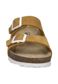 Bruine suède sandaal met twee verstelbare bandjes en witte gespen. Heeft een kurken voetbed en een getextureerde rubberen zool voor grip.
