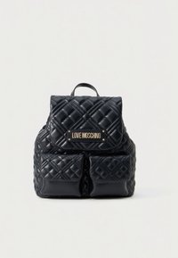 Quiltet svart ryggsekk i kunstlær med gullfarget beslag, som har klaff, frontlommer og en logoplate. Glatt tekstur og strukturert form.