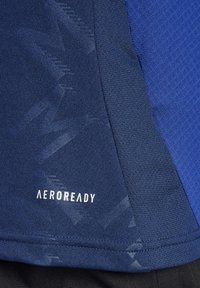 Navy sportshirt van textuurstof, met een subtiel geometrisch patroon en een witte "AEROREADY" logo aan de onderkant.