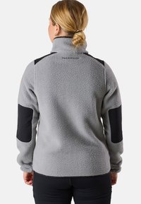 Grå fleece-tröja med hög krage, svarta accentpatchar på axlar och armbågar, samt en märkesetikett på baksidan. Mjuk textur.