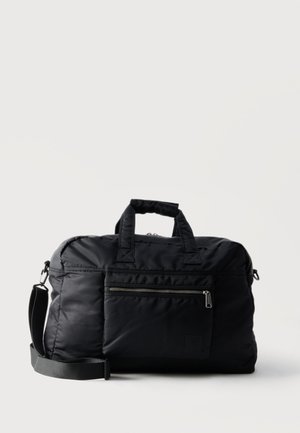 Czarna torba sportowa z nylonu z podwójnymi uchwytami, przednią kieszenią na suwak i regulowanym paskiem na ramię na jasnym, gładkim tle.