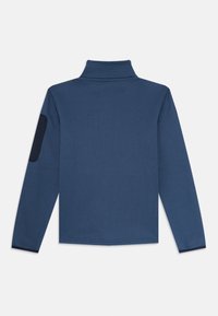 Pullover textured blu navy a maniche lunghe con colletto alto e una macchia scura sul gomito sinistro.