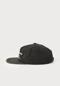 Sapca din denim negru cu coroana structurată și margine curbată. Prezintă un branding brodat alb pe față. Material texturat, curea ajustabilă.