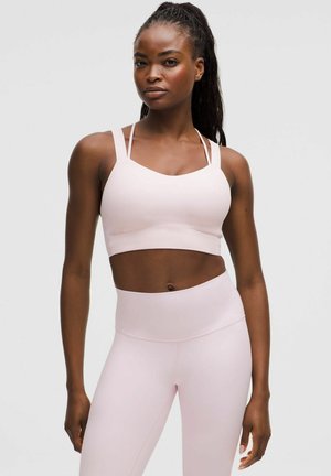Light pink sports bra with wide straps and a scoop neckline, paired with high-waisted light pink leggings, both in a smooth texture.