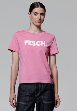 Roze katoenen T-shirt met korte mouwen, voorzien van grote witte tekst die "FESCH" zegt. Gladde textuur en een ronde halslijn.