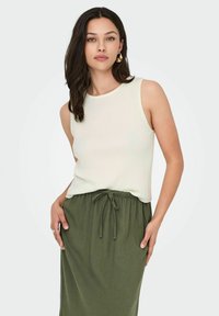 Geribbeld crèmekleurig tanktop met een ronde hals, gecombineerd met een olijfgroene rok met koordjes. Soepele stof, casual pasvorm.