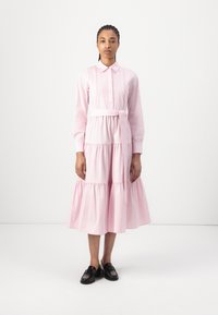 Vestido rosa claro feito de algodão, com gola, fecho de botões na frente, mangas longas, saia em camadas e um cinto na cintura para um detalhe adicional.