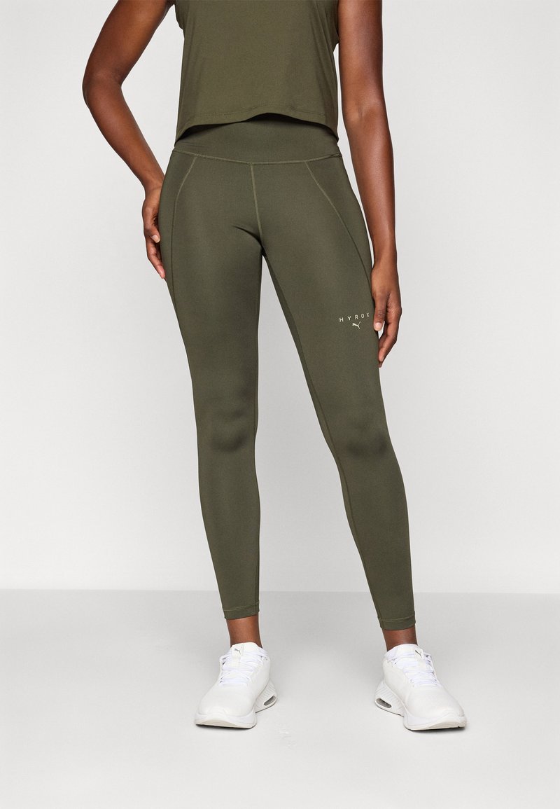 Olivgrüne Leggings mit glatter Textur und figurbetontem Design. Sie verfügen über einen hohen Taillenbund und ein dezentes weißes Logo in Hüfthöhe.