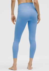 Gaiši zili augstiem legingiem ar gludu, stiepļu audumu, šauriem ankļu garumiem un bezšuvju dizainu jostas un sānu daļās.