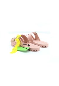 Sandali in gomma rosa chiaro con design perforato, cinturino regolabile e fibbia in tono dorato. Presentano un'etichetta gialla brillante e un'etichetta verde.
