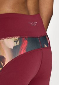 Burgundi aktív sportleggings virágmintás panellel. A "Ted Baker Sport" logó a deréknál. Sima textúra.