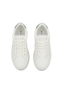 Sneakers bianchi in pelle con una finitura liscia, caratterizzati da un accento verde chiaro sul tallone e un design classico con lacci.