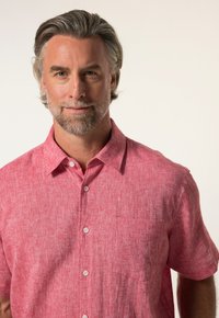 Camicia a maniche corte con bottoni in tessuto rosso testurizzato con un motivo sobrio; presenta un colletto e una tasca sul petto.