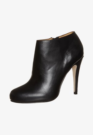 Black leather ankle boot with a pointed toe, high stiletto heel, and a smooth texture. Features a subtle zipper on the back for closure.