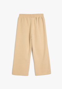 Beige wijde broek van zachte katoen. Voorzien van een elastische tailleband en een gladde textuur. Geen zichtbare patronen of accenten.