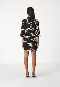 Abito nero con motivo astratto ondulato beige, maniche corte e vestibilità rilassata, realizzato in tessuto leggero, lungo fino a metà coscia.