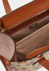 Borsa a tracolla in pelle color tan con motivo a fiori intrecciato. Presenta un ampio interno, una tasca con zip e il marchio GUESS sulla fodera.