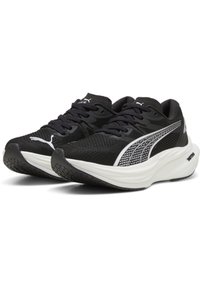 Zapatos deportivos negros de tela de malla con un logo blanco de Puma y detalles en blanco. Cuentan con una suela acolchada y una suela de goma texturizada.
