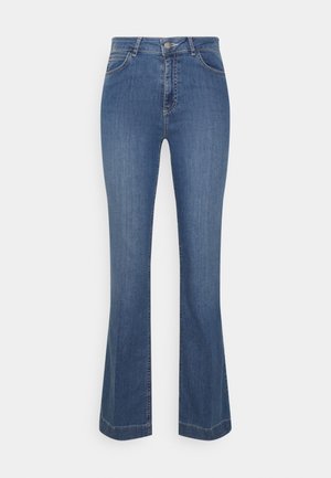 Niebieskie dzwony z wysokim stanem wykonane z denimu, wyposażone w przednie kieszenie, subtelne przeszycia i gładką fakturę. Wygodnie leżą na talii.