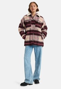Shacket lavet af uldblanding i en cremefarve, burgunder og pink plaid. Har to brystlommer, knaplukning og en shearling krave.