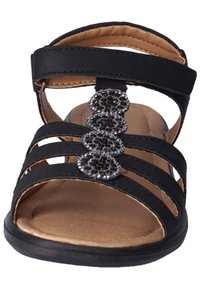 Černé sandály s mnoha páskovým designem, které mají dekorativní skupinu kamenů na přední straně. Hladká kožená textura a polstrovaná podrážka.