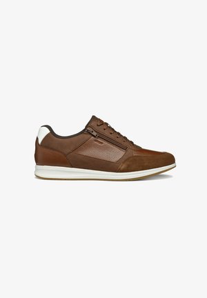 Sneaker en cuir marron et en daim avec semelle en caoutchouc. Présente un panneau texturé, un accent blanc au talon et un système de laçage avec une fermeture éclair sur le côté.