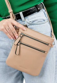 Borsa a tracolla beige realizzata in pelle testurizzata, con tre tasche esterne con zip e una tracolla sottile e regolabile.