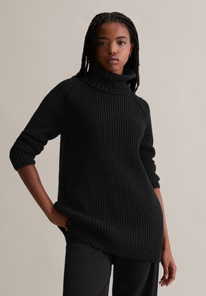 Zwarte gebreide trui met een hoge, omgeslagen kraag. Heeft een gestructureerd oppervlak, lange mouwen met omgeslagen manchetten en een ontspannen pasvorm.