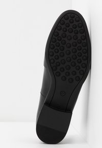 Semelle de chaussure en cuir noir avec motifs circulaires antidérapants et talon texturé, taille 37 marquée près de la voûte plantaire.