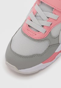 Baskets grises avec une tige en mesh ornée d'accents roses et de lacets blancs. Semelle épaisse avec un léger rembourrage et une texture lisse.