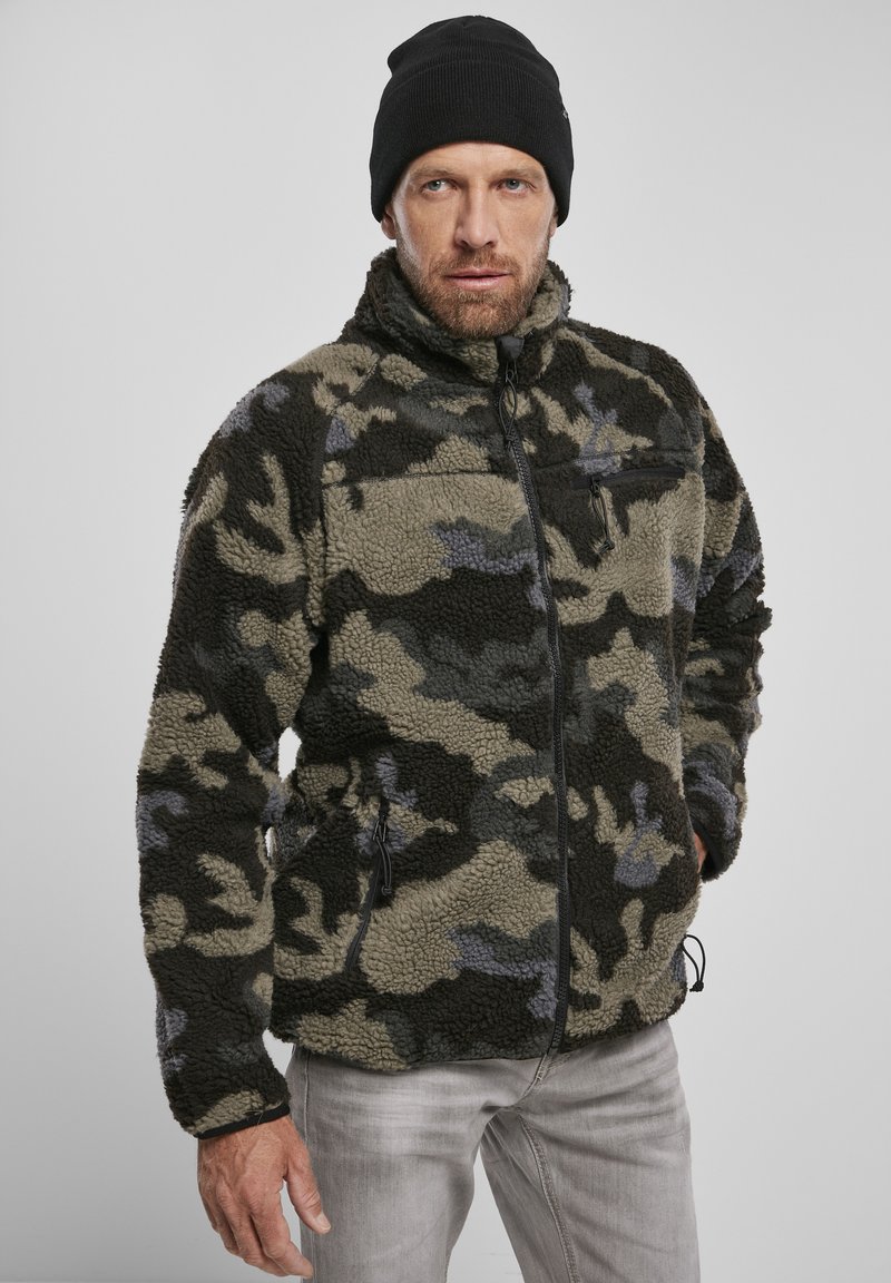 Camouflage fleece jacket in shades of green, gray, and black. Features a high collar, front pockets, and a zip closure. Textured fabric.
