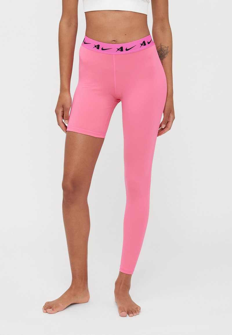 Roze tajice s asimetričnim rezom, koje imaju široku elastiku s crnim naglascima logotipa Nike. Izrađene od rastezljivog, glatkog materijala.