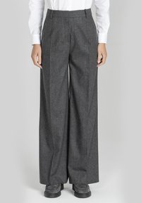 Szare, szerokie spodnie w kant z teksturowanej tkaniny, z zakładkami z przodu, dwiema przednimi kieszeniami oraz paskiem z pętelkami. Połączone z ciemnym obuwiem.