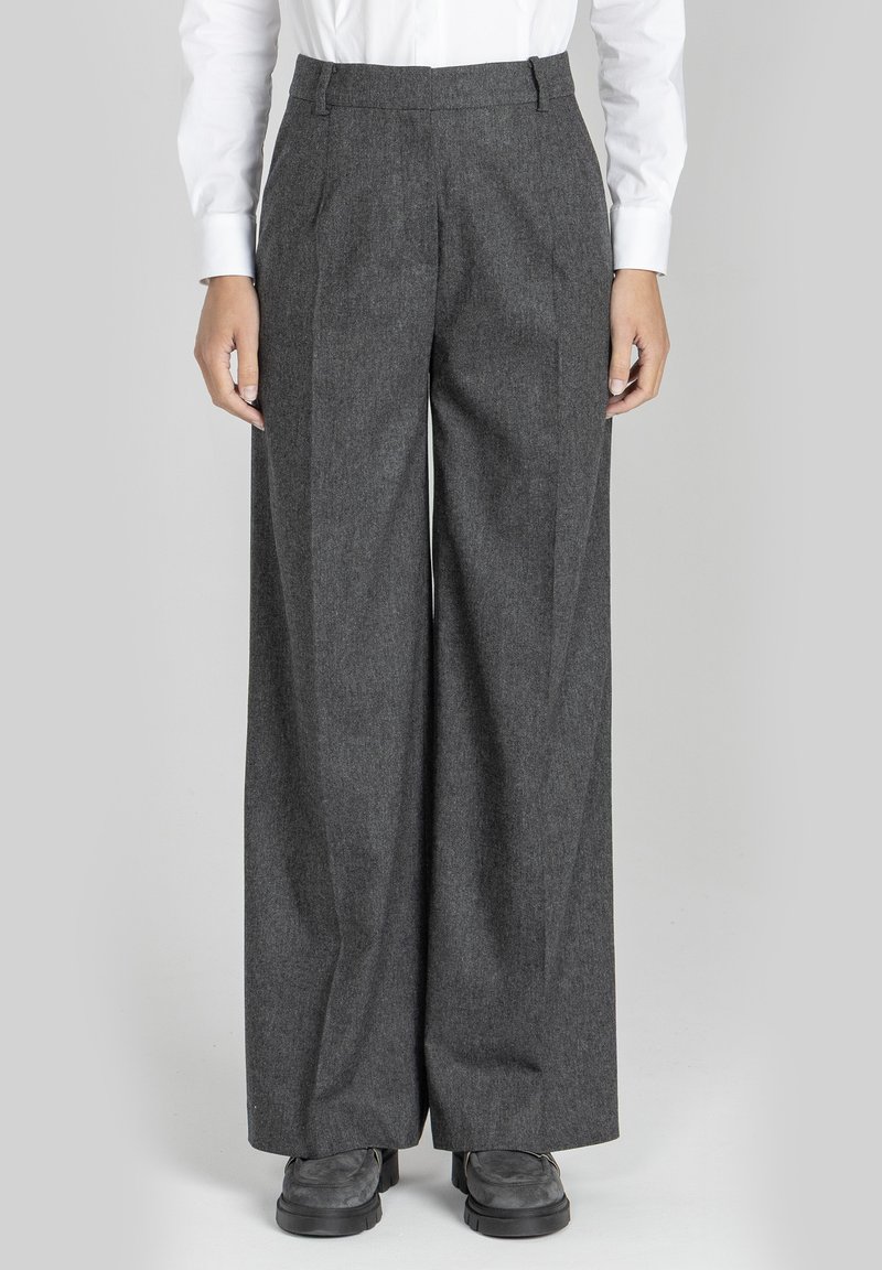 Szare, szerokie spodnie w kant z teksturowanej tkaniny, z zakładkami z przodu, dwiema przednimi kieszeniami oraz paskiem z pętelkami. Połączone z ciemnym obuwiem.