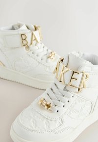 Hvide høje sneakers lavet af tekstureret læder, med guldfarvet hardware, prægede mønstre og unikke snører med en sløjfe.