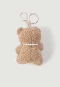 Porte-clé en peluche brun en forme d'ours avec un collier en perles et un fermoir et anneau en métal argenté, sur un fond blanc.
