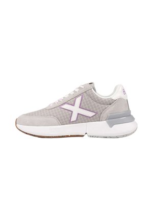 Zapatilla gris y blanca con detalles morados, gran logo lateral en forma de X, suela blanca y soporte de talón gris, vista desde un lado sobre un fondo blanco.