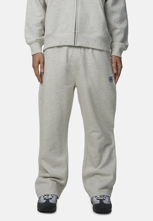 Pantaloni della tuta grigio chiaro in tessuto morbido, con vita con coulisse, vestibilità rilassata e un piccolo logo blu sull'anca sinistra.