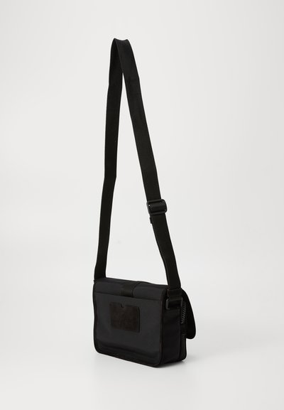Geantă de umăr neagră, într-o formă rectangulară plată, fabricată dintr-un material durabil, cu curea ajustabilă și un mic buzunar frontal.