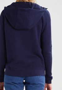 Námořnická modrá mikina z jemné směsi bavlny, s kapucí na šňůrky a vroubkovanými manžetami. Dokončeno pohodlným, volným střihem.