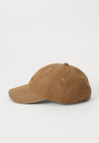 Casquette de baseball en tissu brun avec une visière incurvée, des coutures ton sur ton et un logo brodé sur le devant ; elle comporte six trous de ventilation en œillet.
