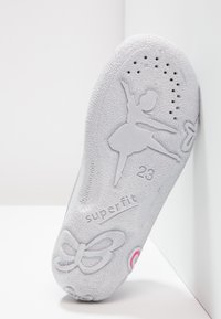 Jasnoszara podeszwa buta z teksturowaną powierzchnią, z sylwetką baletnicy, brandingiem "superfit", rozmiarem "23" oraz wzorem kokardy.