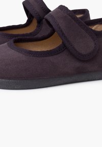 Zapatos de tela morados oscuros con textura suave, punta redondeada, abertura elástica y correa de Velcro para un cierre seguro. Suela de goma.