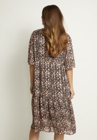 Kleid mit floralem Druck aus leichtem, dunklem Stoff; verfügt über kurze Ärmel, eine geraffte Taille und einen gestuften Rock mit pinken und weißen Blumenmustern.