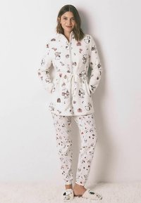 Weißes Fleece-Pyjama-Set mit einer Jacke mit Knöpfen und gemusterten Hosen. Das Design umfasst Illustrationen von Figuren, Geschenken und saisonalen Motiven.