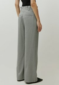 Wijdvallende broek in een zwart-wit geruit patroon, met een hoge taille, twee achterzakken en een gladde textuur.