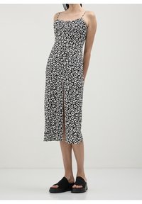 Šaty s leopardím potiskem v černobílé barvě, na tenkých ramínkách, těsně přiléhající korzet a střední délka s rozparkem na boku. Obsahuje ploché černé sandály na klínku.