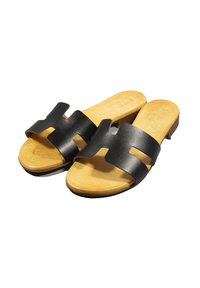Infradito in pelle nera con design aperto, caratterizzati da dettagli ritagliati e una soletta di colore legno naturale. Suola piatta.
