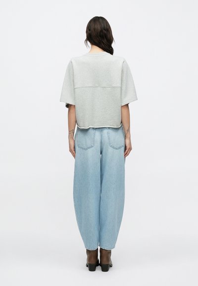 Ανοιχτό γκρι κοντομάνικο μπλουζάκι με οριζόντια ραφή, συνδυασμένο με ανοιχτό μπλε τζιν παντελόνι φαρδιάς γραμμής με ξεθωριασμένη υφή και δύο πίσω τσέπες.